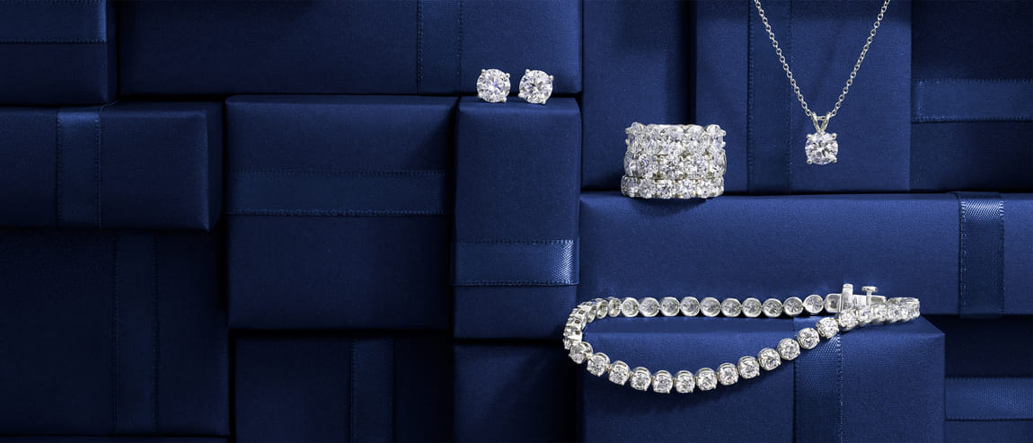 Diamond earrings, rings, necklace, and bracelet on blue boxes